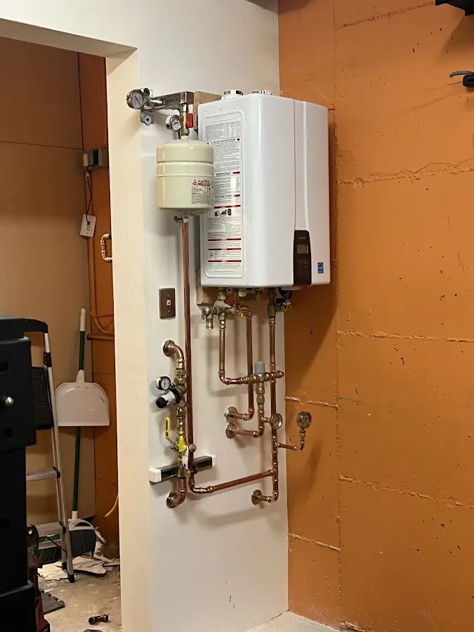 Plumbing technician inspecting water heater connections in Comanche